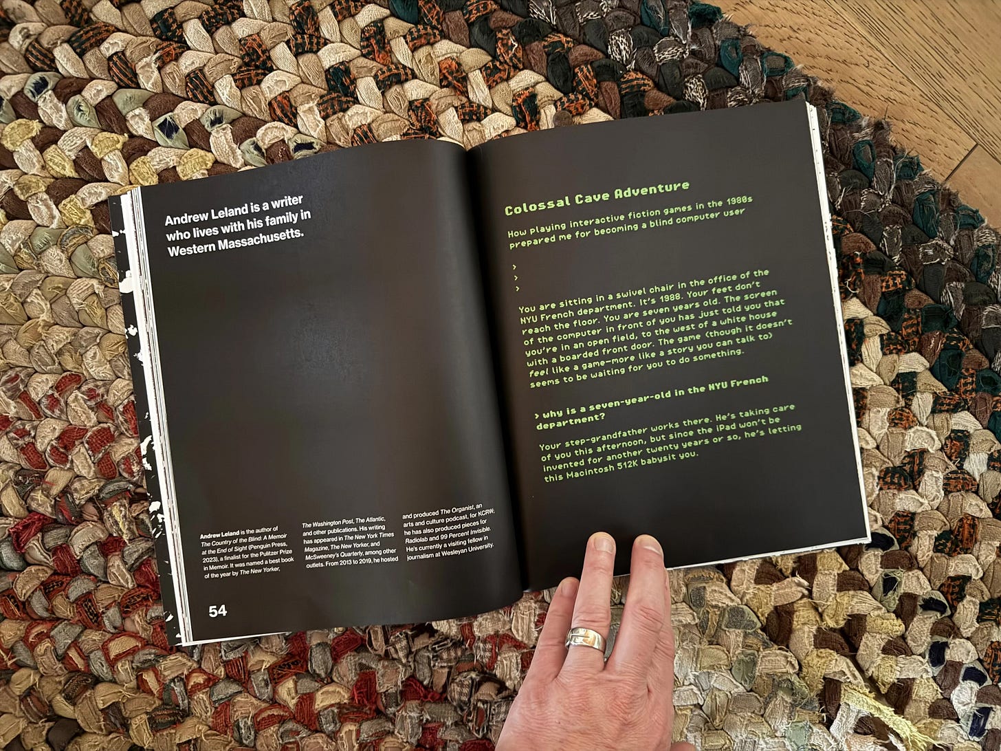 A photo of the first page of this piece in the magazine, held open by a white hand on a nice woven rug