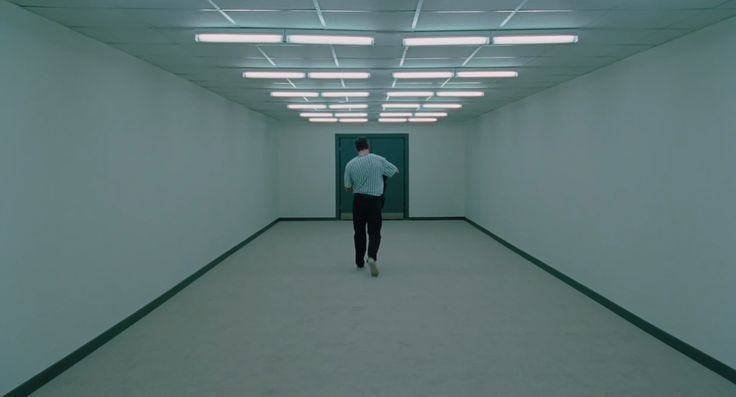 This may contain: a man is walking down the hallway in an empty building with bright lights on the ceiling