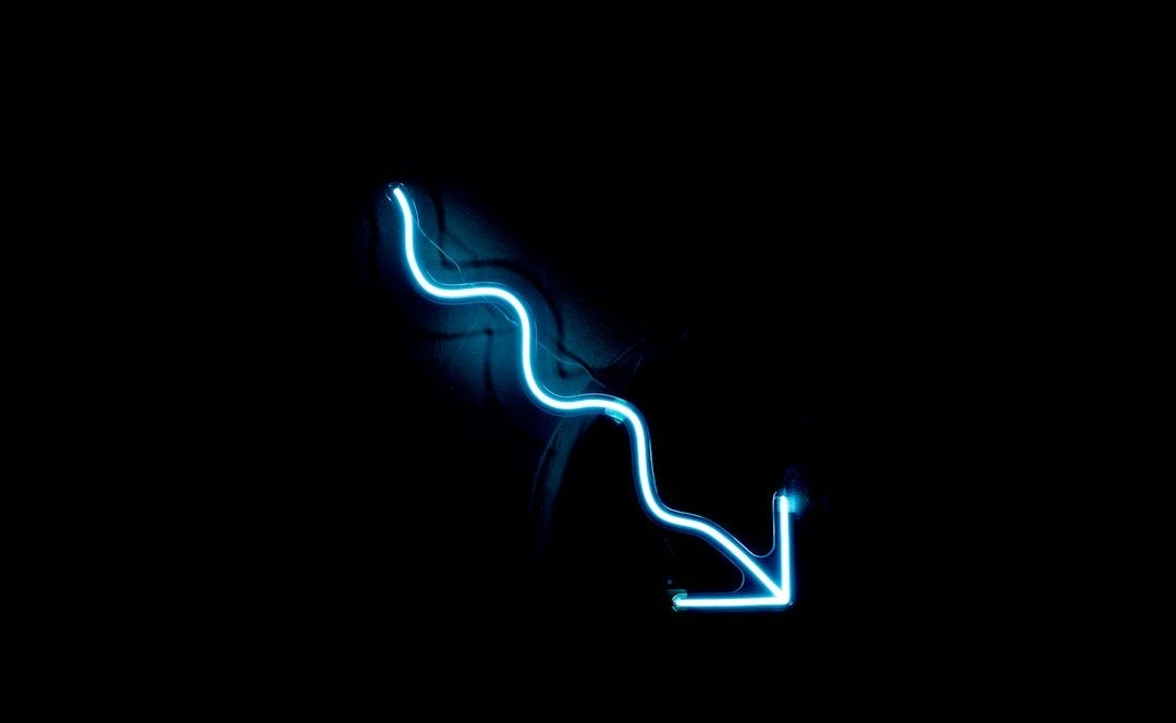 a blue neon sign on a black wall a blue neon sign on a black wall