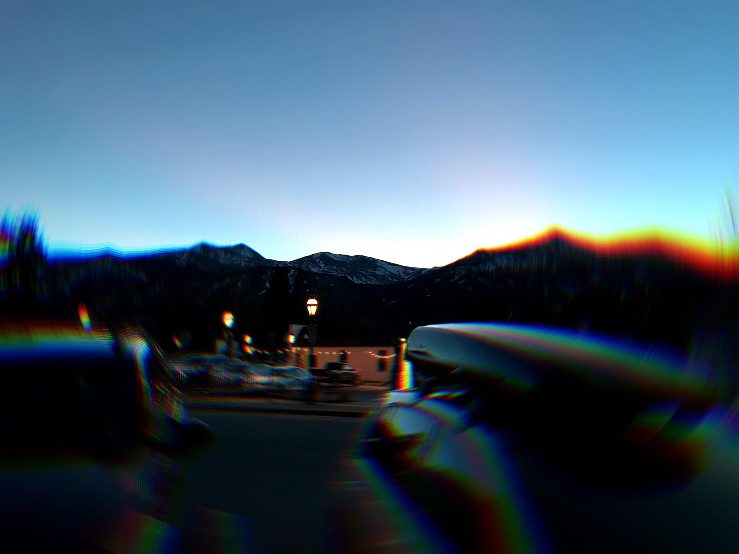 Blurry twilight photo of a mountain town street with streetlights glowing and snowy peaks in the distance—capturing the quiet ache of transition, the beauty of disorientation, and the search for clarity after spiritual confusion and burnout.