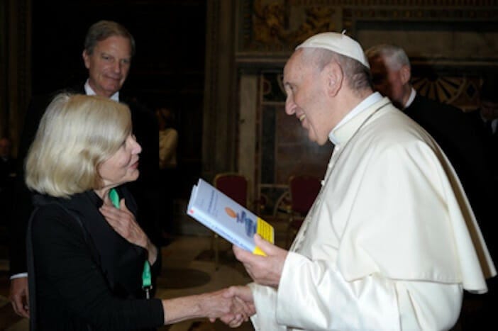 Clair Brown shakes hands with Pope Francis, who is holding a copy of her book, Buddhist Economics.