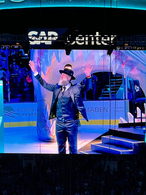 Photo 1: Image of woman in Sharks jersey smiling outside arena; Photo 2: Image of Joe Thornton ice sculpture; Photo 3: Image of Joe Thornton coming through Shark head on ice; Photo 4: image of two women smiling with ice rink behind them; Photo 5: Image of Shark head and chairs on ice for ceremony; Photo 6: Image of Joe Thornton on big screen; Photo 7: Image of Thank You Joe box where jersey was raised with family behind it; Photo 8: Image of ice rink with Shark head and players; Photo 9: Image of #12 and #19 jersey's hanging in the rafters of the arena