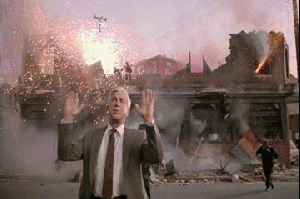 A man says nothing to see here as a building explodes behind him A man says nothing to see here as a building explodes behind him