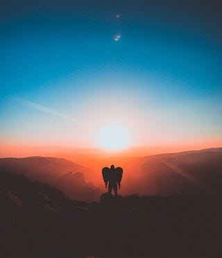 Silhouette of man with wings standing on a hill. The sun is rising or setting directly over his head. Silhouette of man with wings standing on a hill. The sun is rising or setting directly over his head.