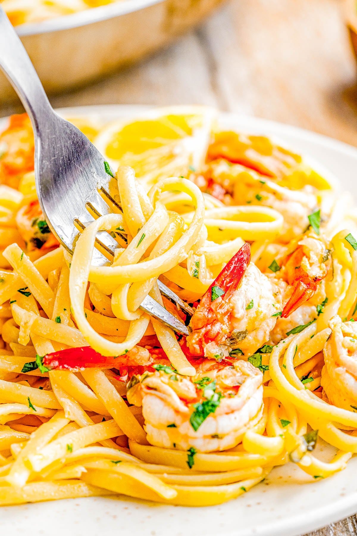 A fork twirling a bite of shrimp scampi pasta on a plate. 