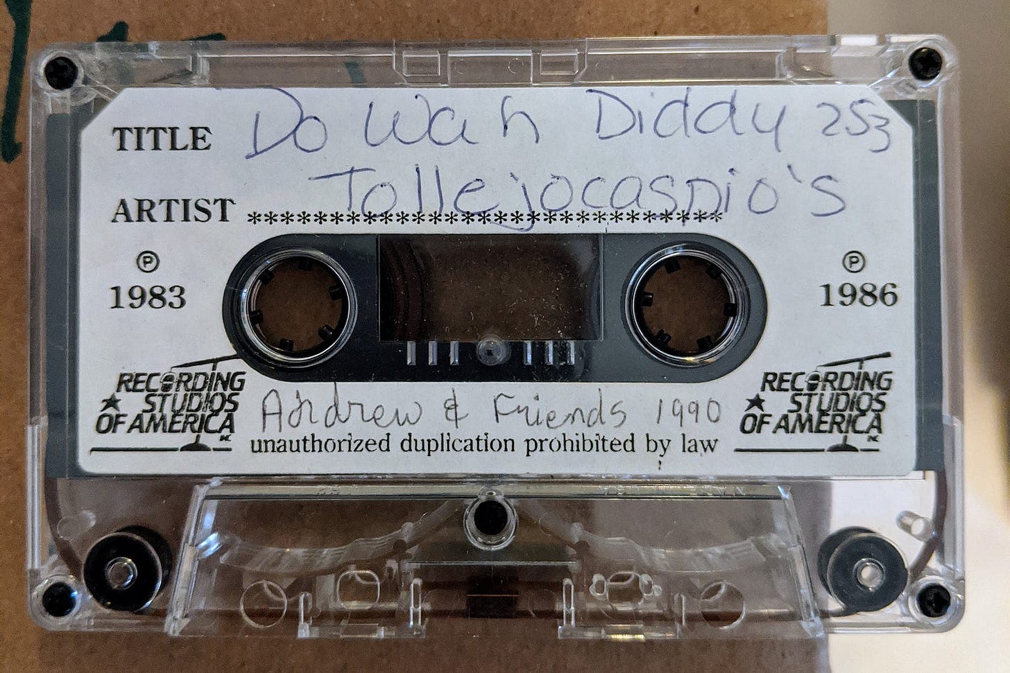 A vintage cassette tape with handwritten label reading "Do Wah Diddy 253" by "Tollejocasdio's," marked "Andrew & Friends 1990" from Recording Studios of America.