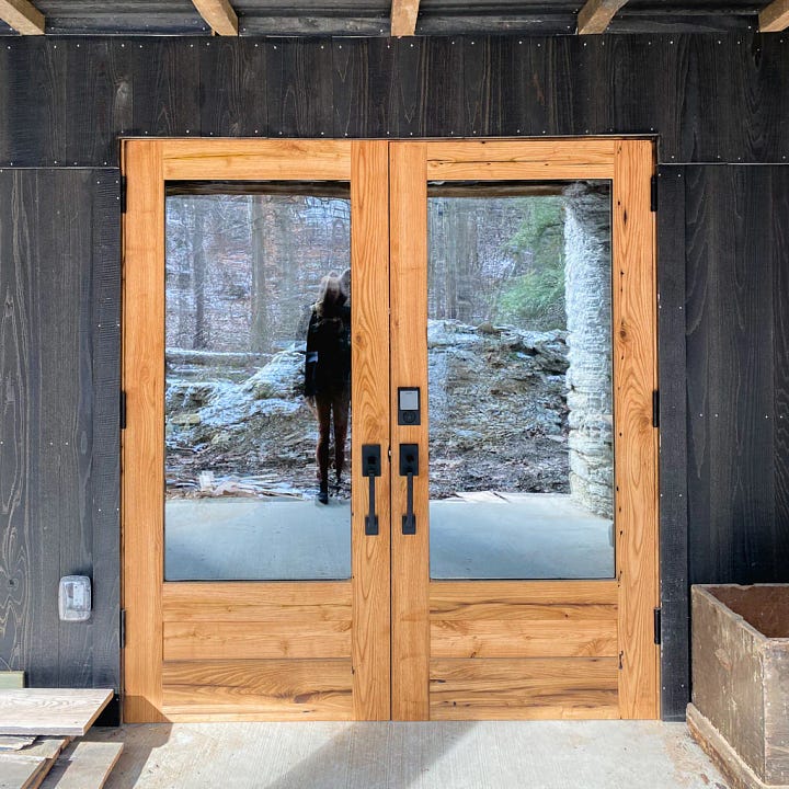 Image of American Chestnut tree beams underneath the barn floor and an image of new wood and glass doors which is the entrance to the barn, doors made by Walter Kent.