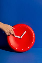 A human hand going to move the hands back on a clock face. A human hand going to move the hands back on a clock face.