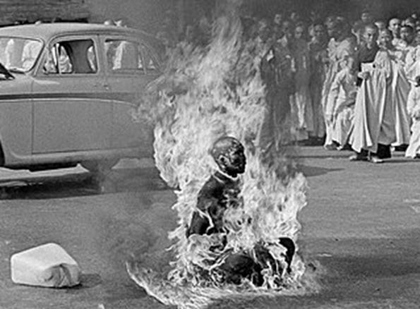 A person on fire in front of a crowd of people

Description automatically generated