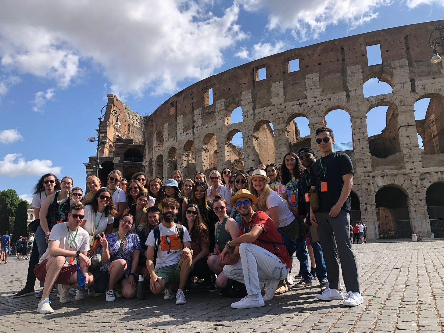 A group of young adults posing in front of the Colosseum in Rome, Italy