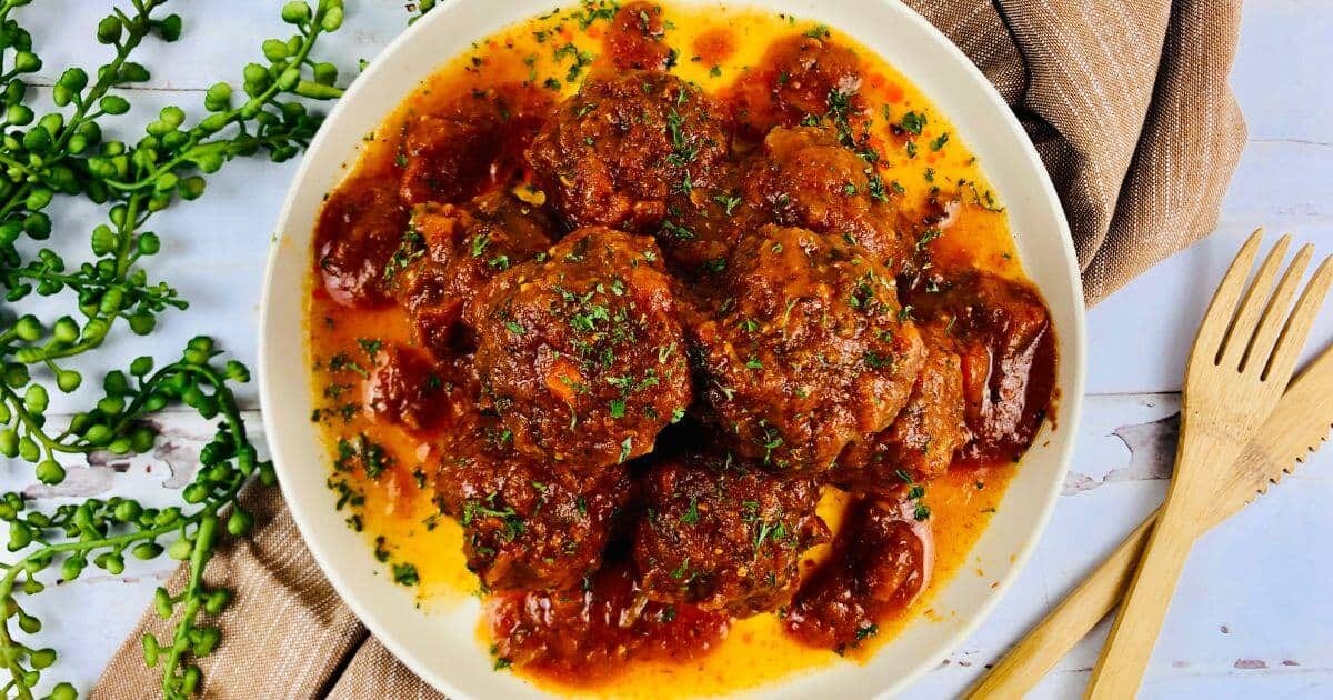 gluten free sausage balls with marinara on white plate.