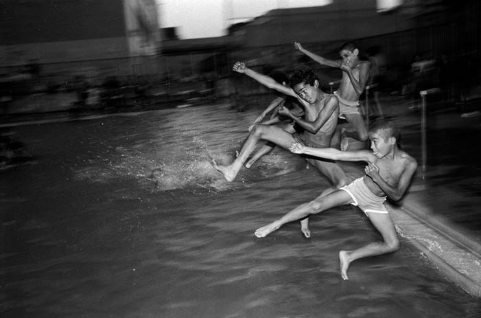 A group of boys running into a pool

Description automatically generated