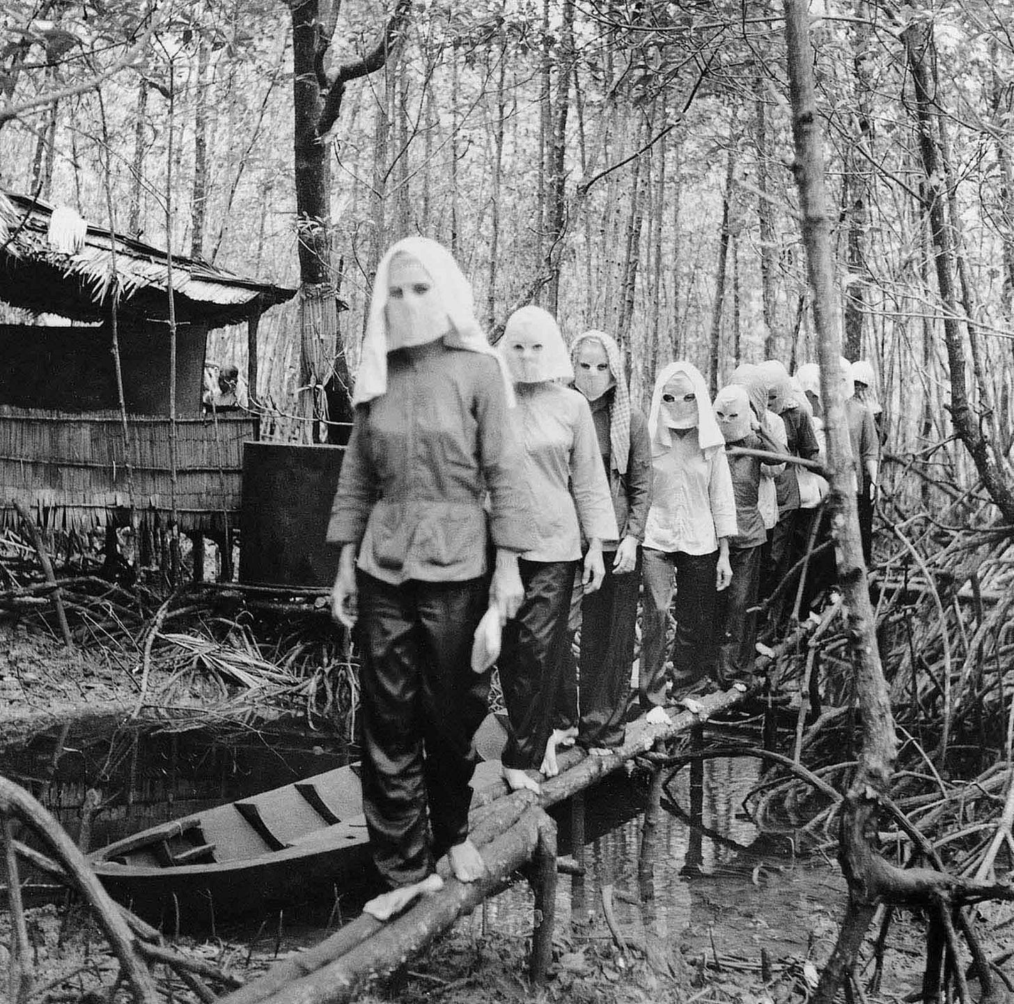 A Viet Cong resistance fighter, their identity concealed by a mask, in a private meeting in 1972 during the Vietnam War.