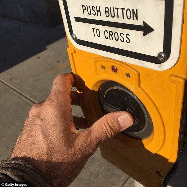 This may contain: a hand is pressing the push button to cross on a yellow and white parking meter