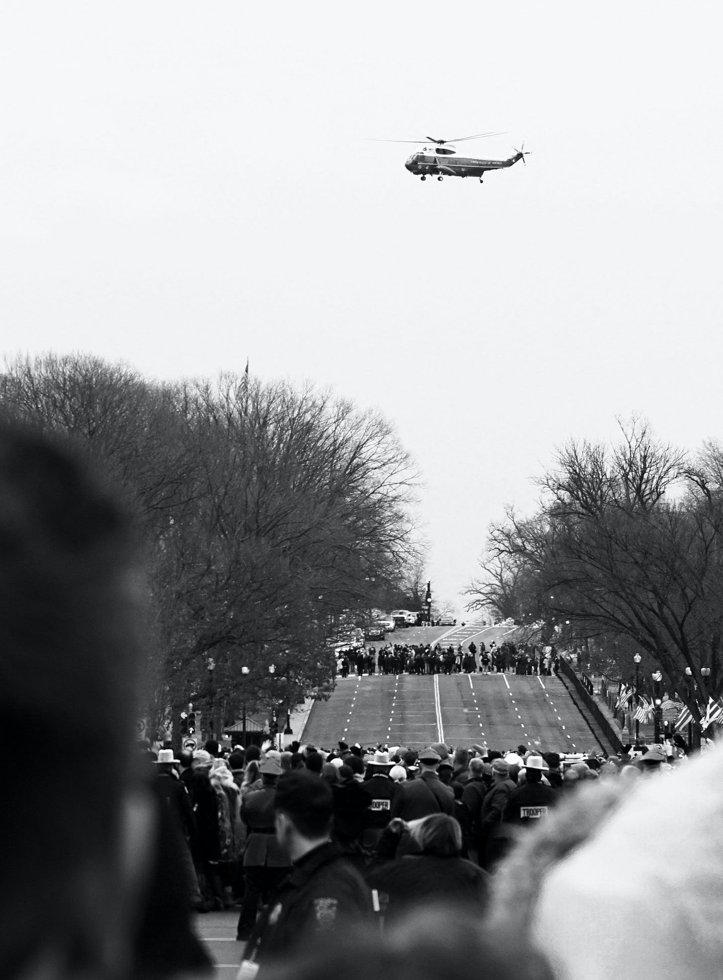 Photo of a government helicopter over the heads of people gathered in a street. Photo of a government helicopter over the heads of people gathered in a street.