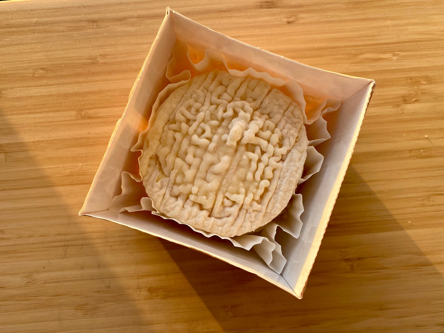 La Tur cheese wheel in its signature "cupcake" packaging: wax paper cup inside of a perfectly fitted small box with no top