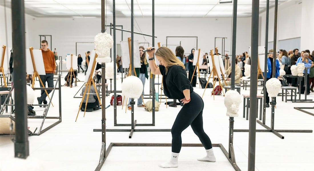 A hall with easels and people working out against black iron frames A hall with easels and people working out against black iron frames