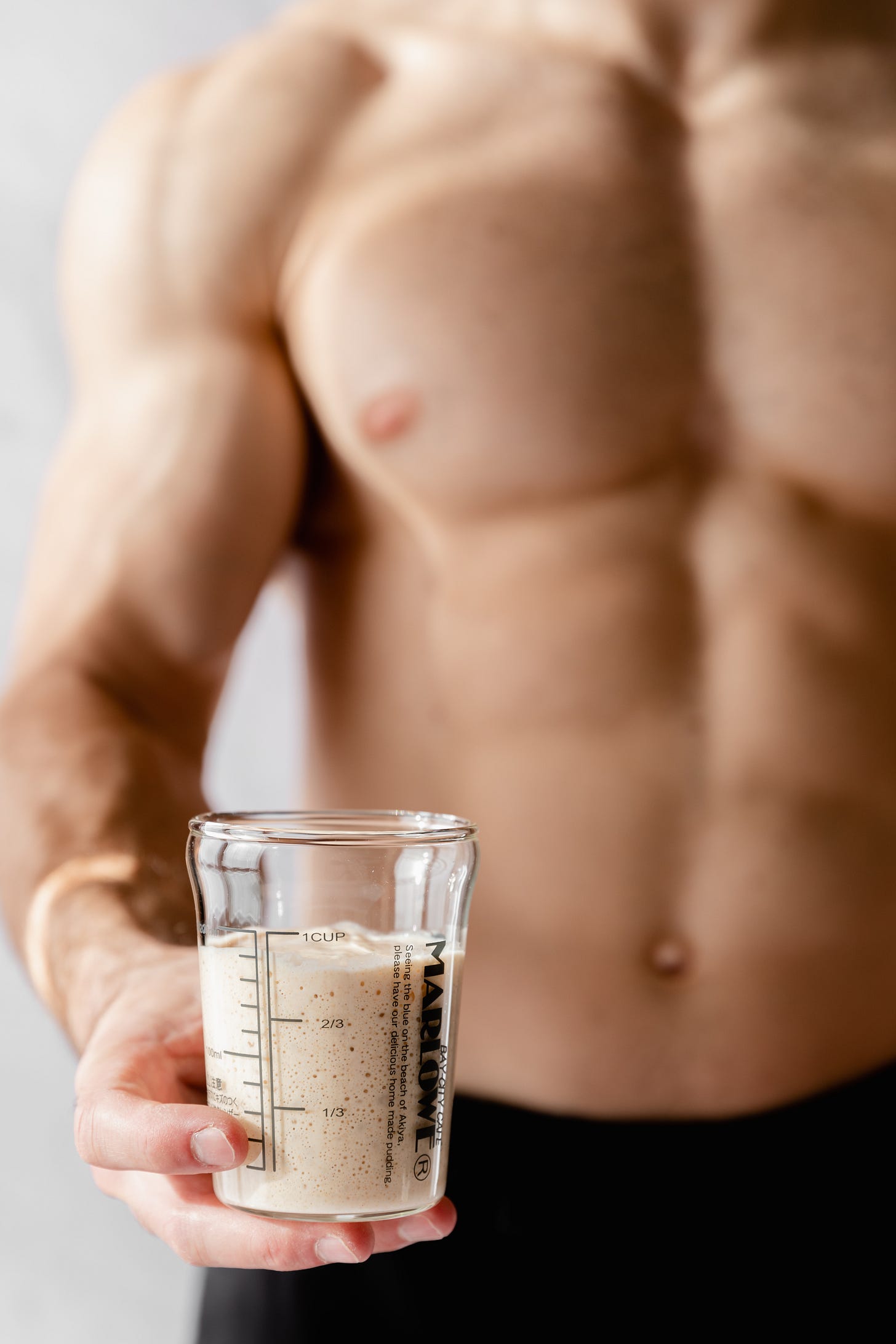 Shirtless man holding glass jar of sourdough starter