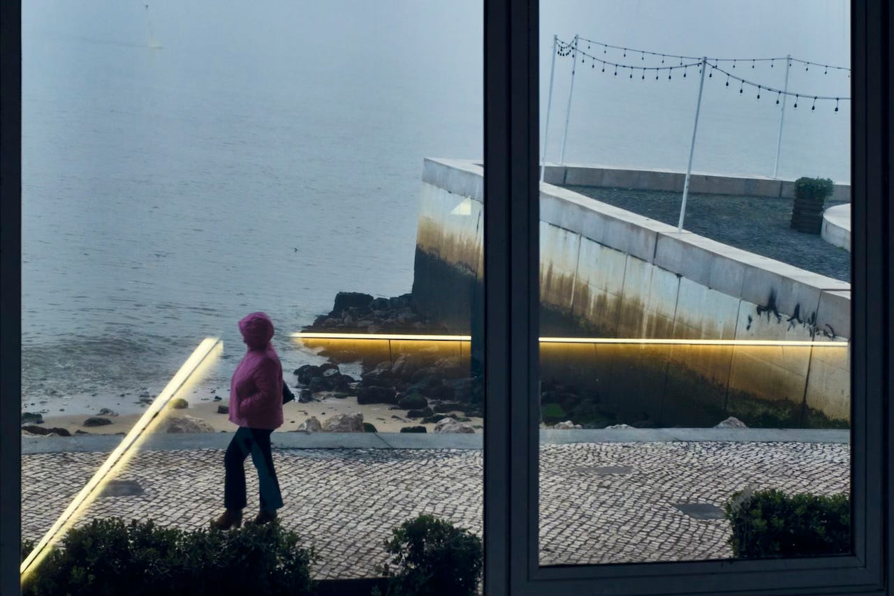 Rays of neon light frame a passer-by on the morning foggy riverside, Lisbon Rays of neon light frame a passer-by on the morning foggy riverside, Lisbon