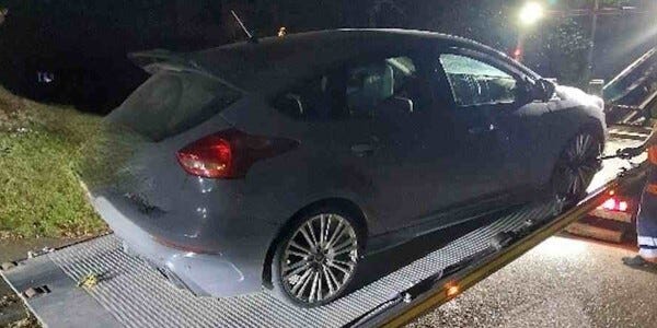 Grey car on a transporter lorry at night