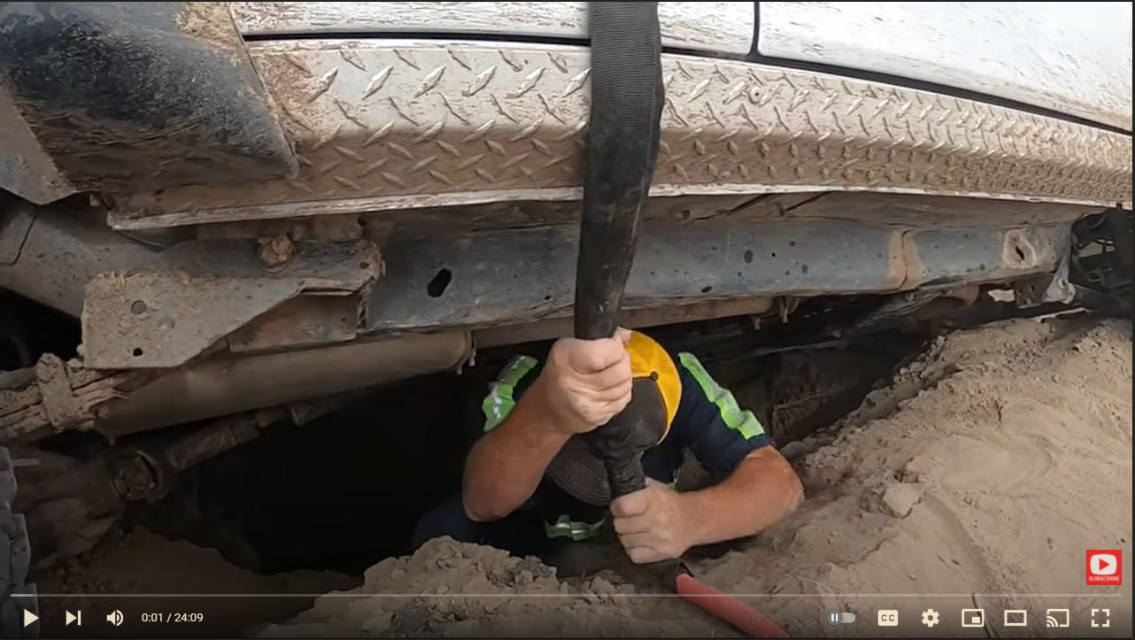 Matt climbing into a sink hole underneath a vehicle.