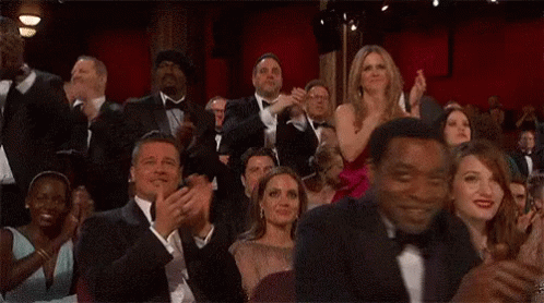 a group of people are sitting in a theatre clapping their hands . a group of people are sitting in a theatre clapping their hands .