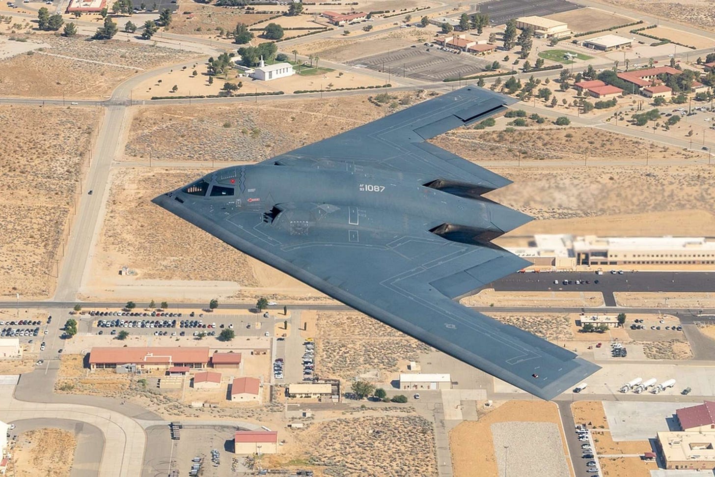 A military jet flying over a desert

Description automatically generated