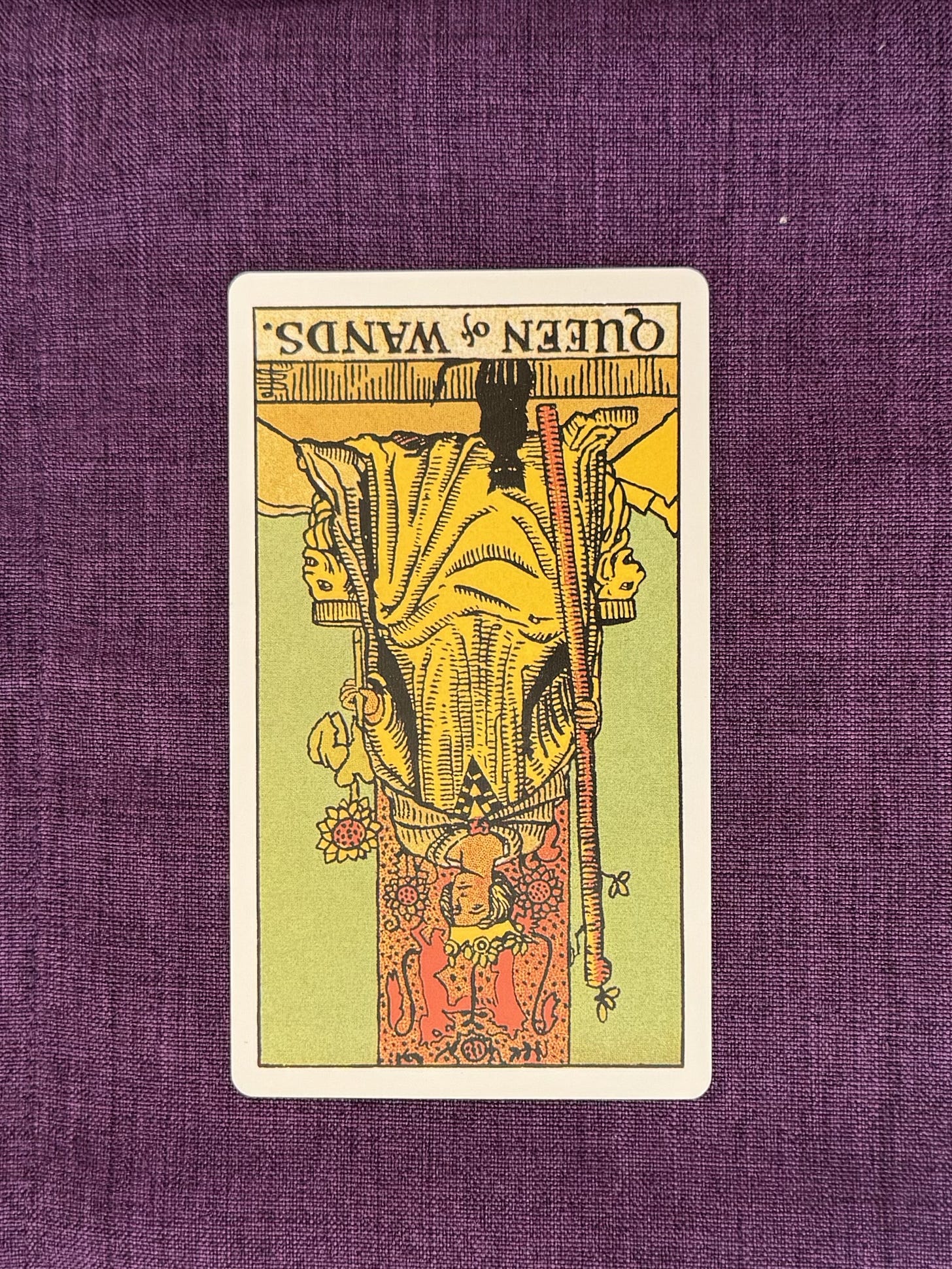 upside down tarot card depicts: A seated figure sits on an ornate throne decorated with carved lions and sunflower designs. The figure wears a crown and a long robe, holding a tall wand upright in one hand and a sunflower in the other. A small black cat sits at the figure’s feet, facing forward. The background shows a clear sky, and the ground is flat and open with no other people present. upside down tarot card depicts: A seated figure sits on an ornate throne decorated with carved lions and sunflower designs. The figure wears a crown and a long robe, holding a tall wand upright in one hand and a sunflower in the other. A small black cat sits at the figure’s feet, facing forward. The background shows a clear sky, and the ground is flat and open with no other people present.