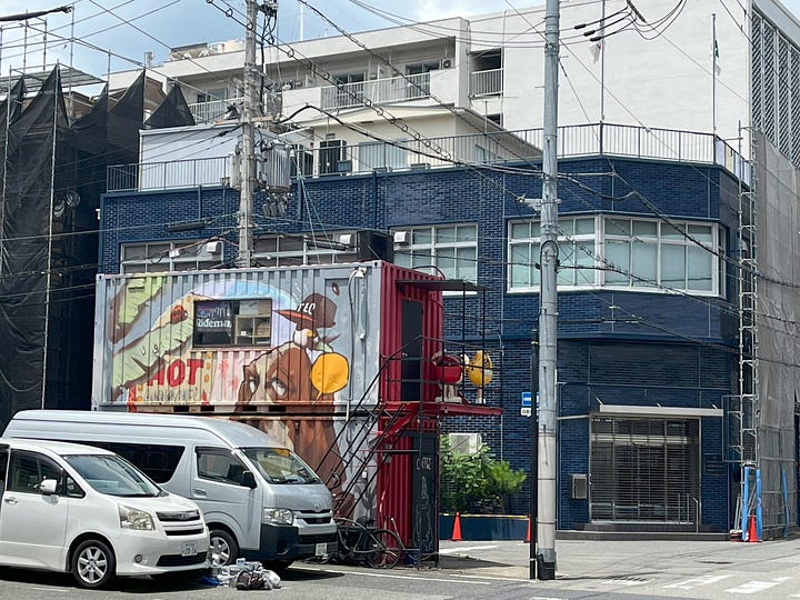 A picture of a shipping container cafe, and a temple entrance with stone statues visible through the gate