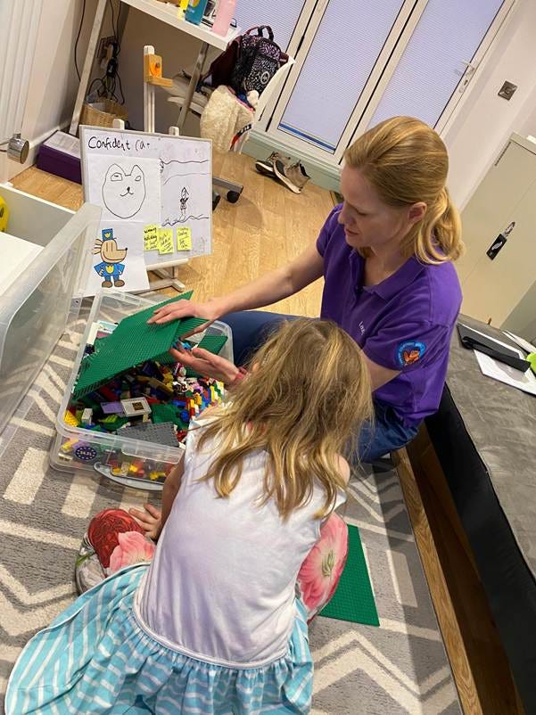 A person and child playing with legos

Description automatically generated