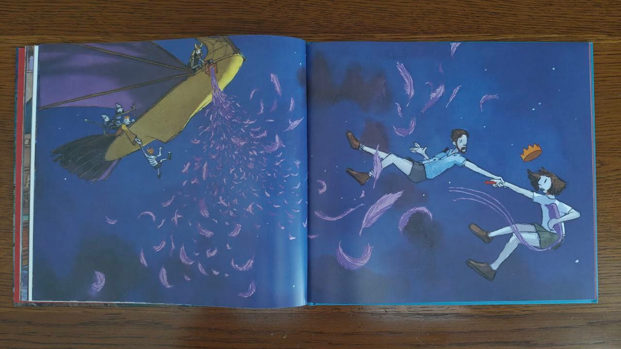 Doppia pagina del libro "Viaggio" di Aaron Becker appoggiata su un tavolo di legno marrone. Un velivolo giallo distrugge il cavallo alato che si dissolve in piume violetto, mentre alcune guardie a bordo catturano il re e un bambino; un adulto e una bambina cadono ma si stringono la mano.
