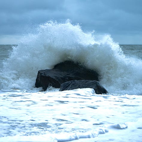 distant green hills sea cliffs and sunset big wave splashing against a rock