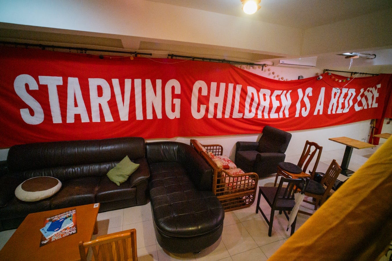 Horizontal photo of a wide banner stretched across the Daybreak basement wall with text reading Starving Children is a Red Line.