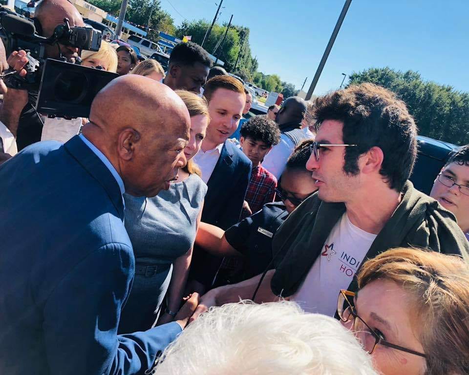 Daniel Cohen shaking hands with John Lewis in 2018. Daniel is wearing an Indivisible Houston shirt. A camera us nearby. So are Congresswoman Lizzie Fletcher and Adam Milasincic.
