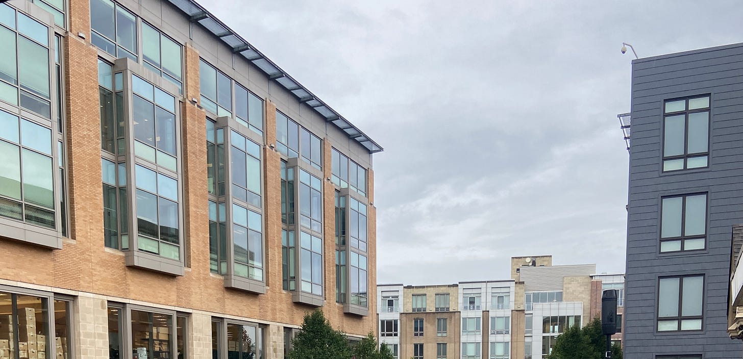 Orange, beige, and grey brick buildings with large windows against a grey sky.