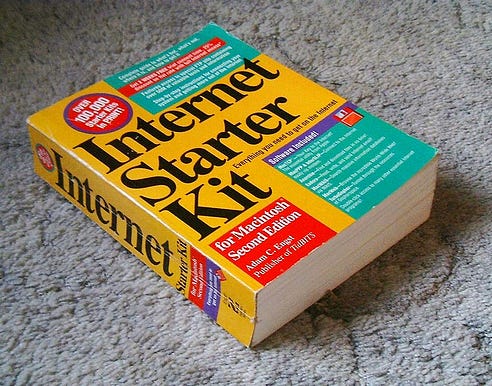 A photo of a large, thick yellow book on a grey carpet. It has 'Internet Starter Kit' on the front and 'for Macintosh Second Edition'.