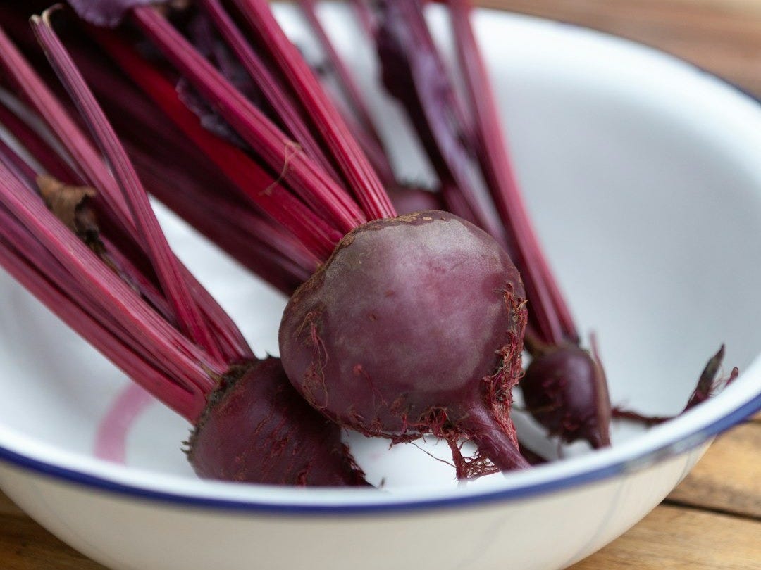 a bowl filled with beets sitting on top of a wooden table a bowl filled with beets sitting on top of a wooden table