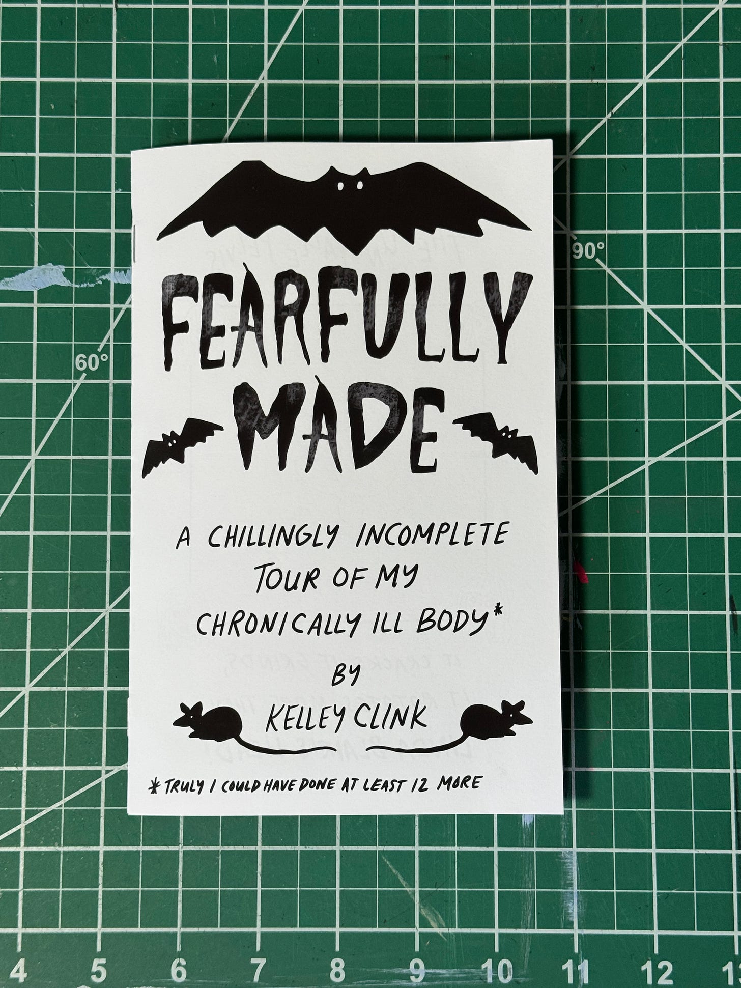 a photo of the zine. there is a large black bat at the top, then the words Fearfully Made in a squiggly black font with two smaller black bats. then regular handwriting reading: a chillingly incomplete tour of my chronically ill body, by Kelley Clink. there are two silhouettes of rats.