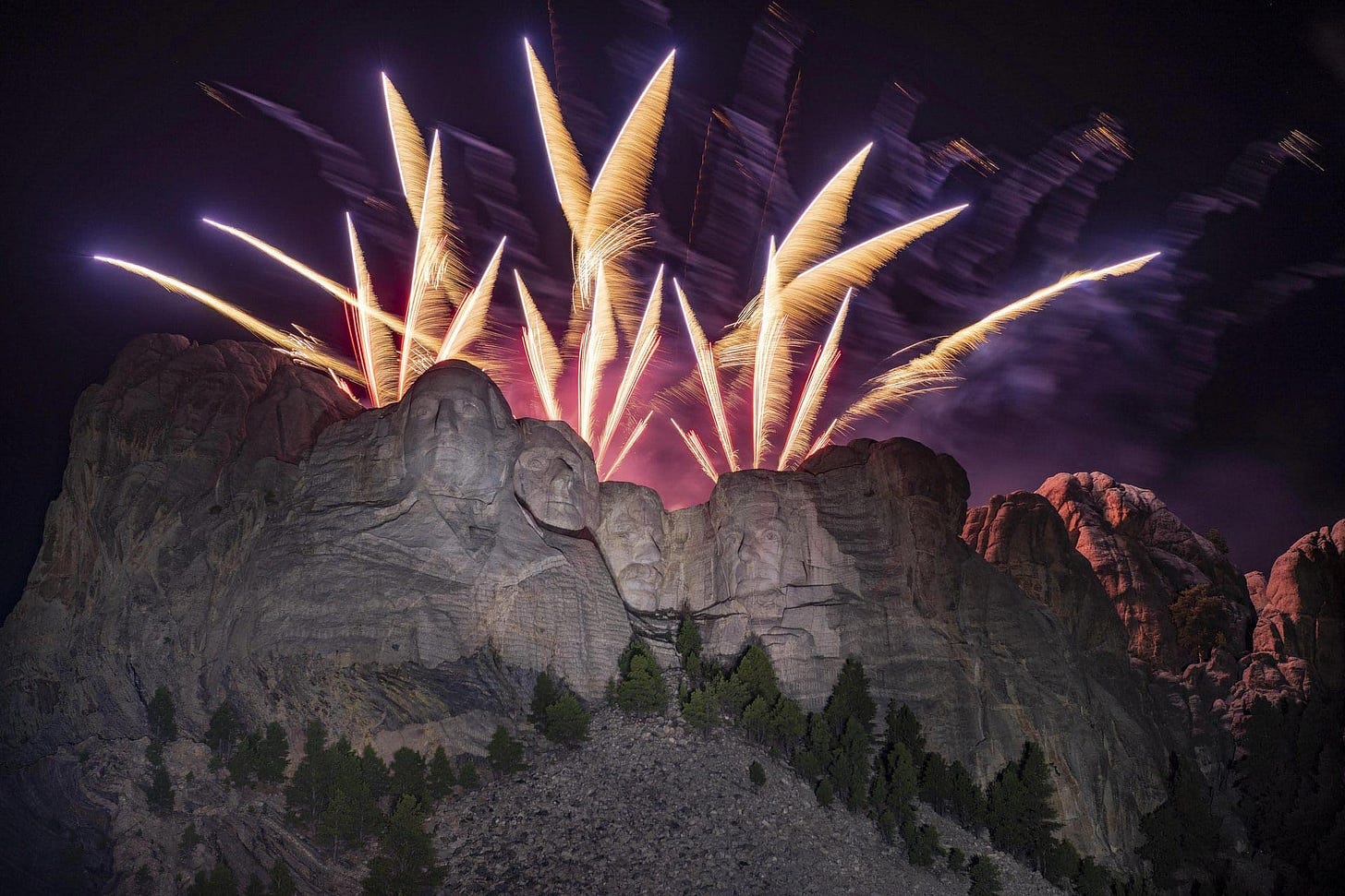 Fireworks explode over Mount Rushmore National Memorial, with the face of the sculpture illuminated by their multicolored light. Fireworks explode over Mount Rushmore National Memorial, with the face of the sculpture illuminated by their multicolored light.