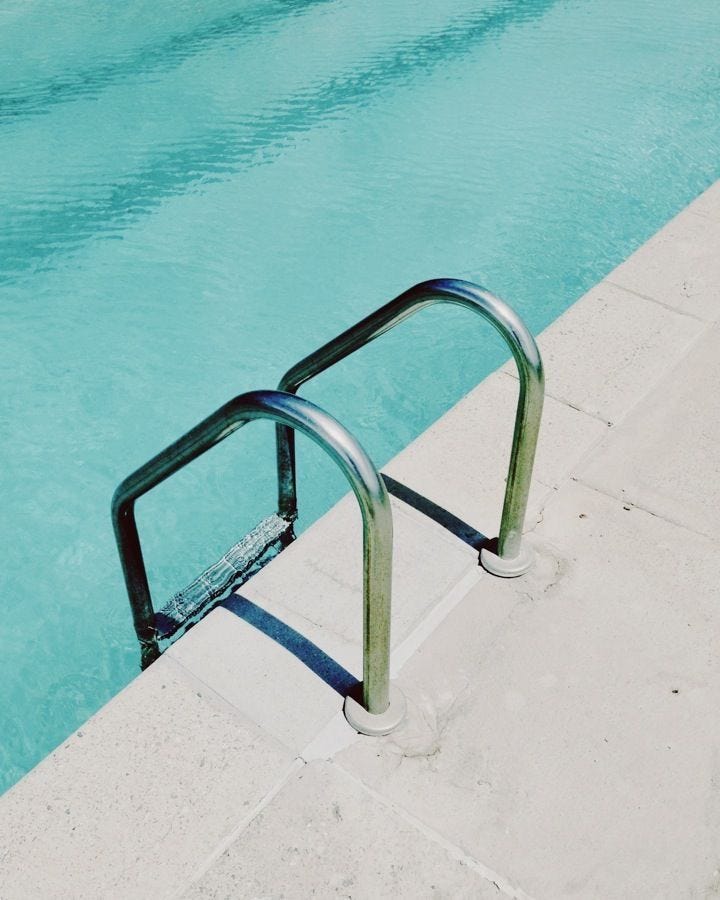 This may contain: an empty swimming pool next to a metal hand rail with water in the back ground