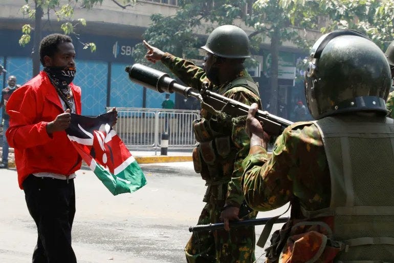 A fearless Kenyan Holding Kenyan flag standing infront of armed police men.