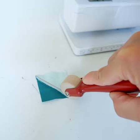 rolling with a seam presser on a table next to a sewing machine