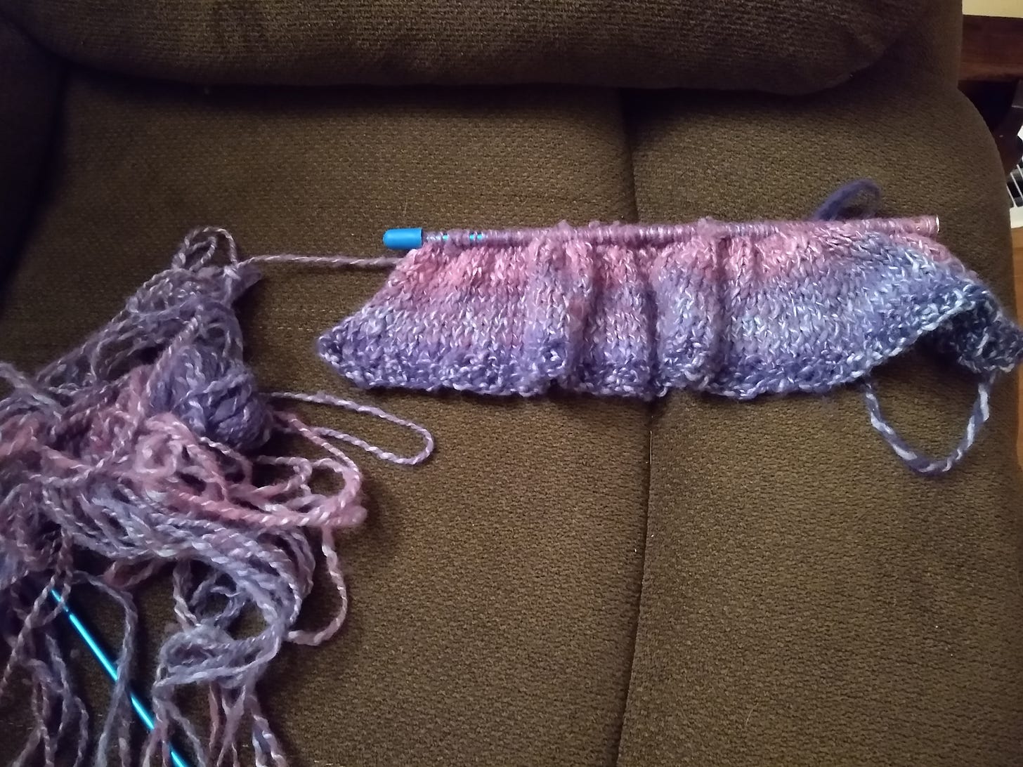 Yarn in shades of purple, pink, and blue -- some knitted up, some all tangled