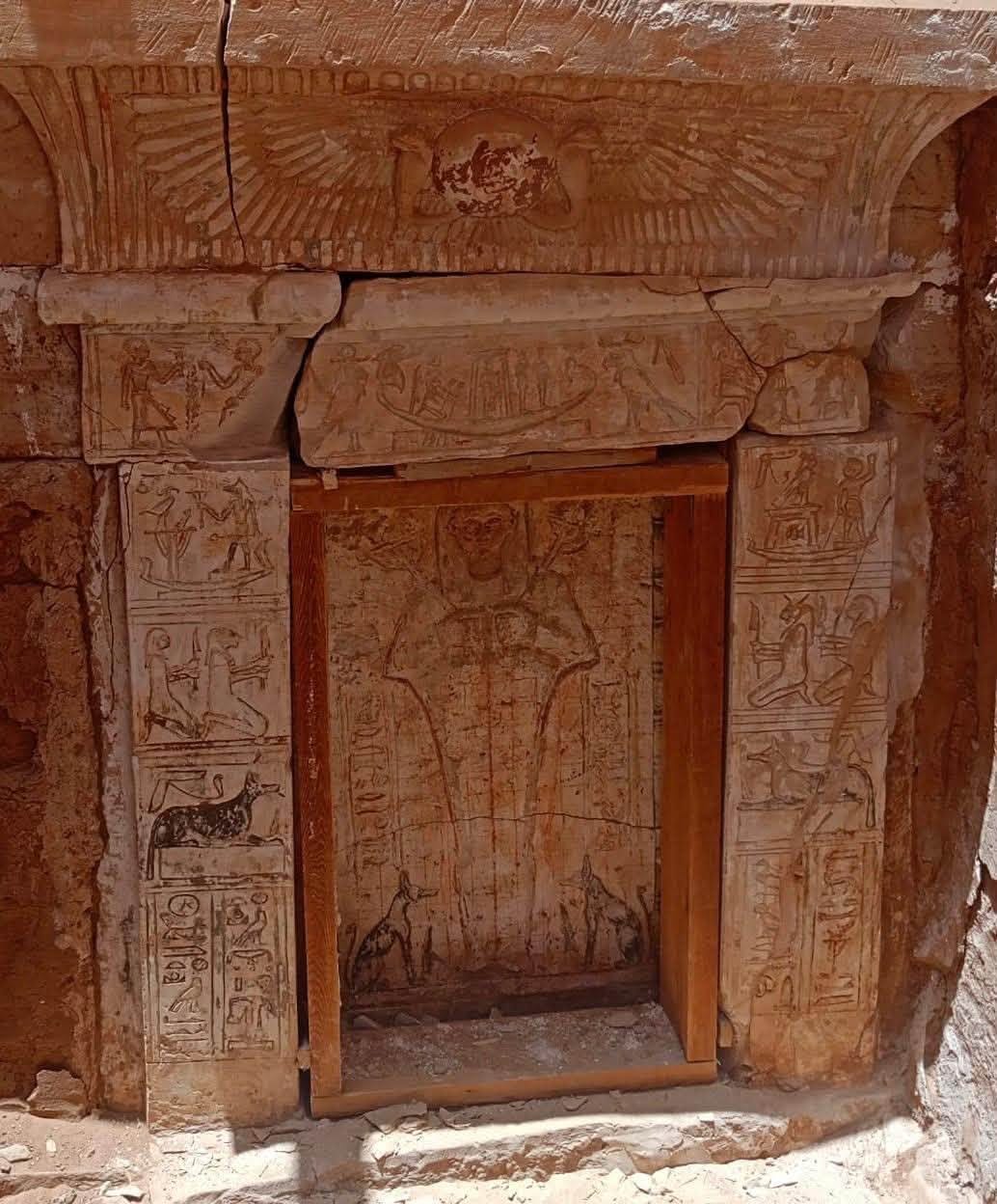 The carved sandstone entrance at Bir el-Shaghala, with the winged sun disc on the cornice and the seventh hour of the Amduat on the lintel.