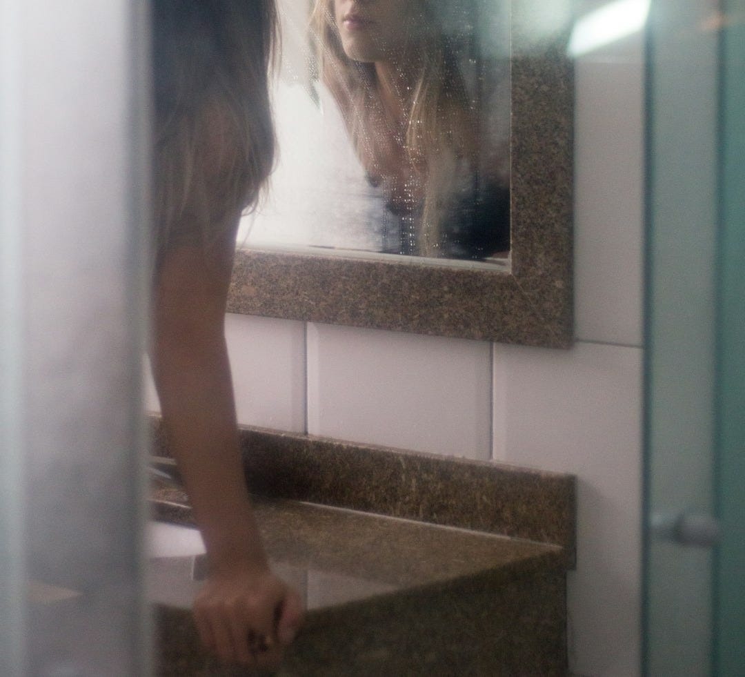woman looking on wall mirror woman looking on wall mirror