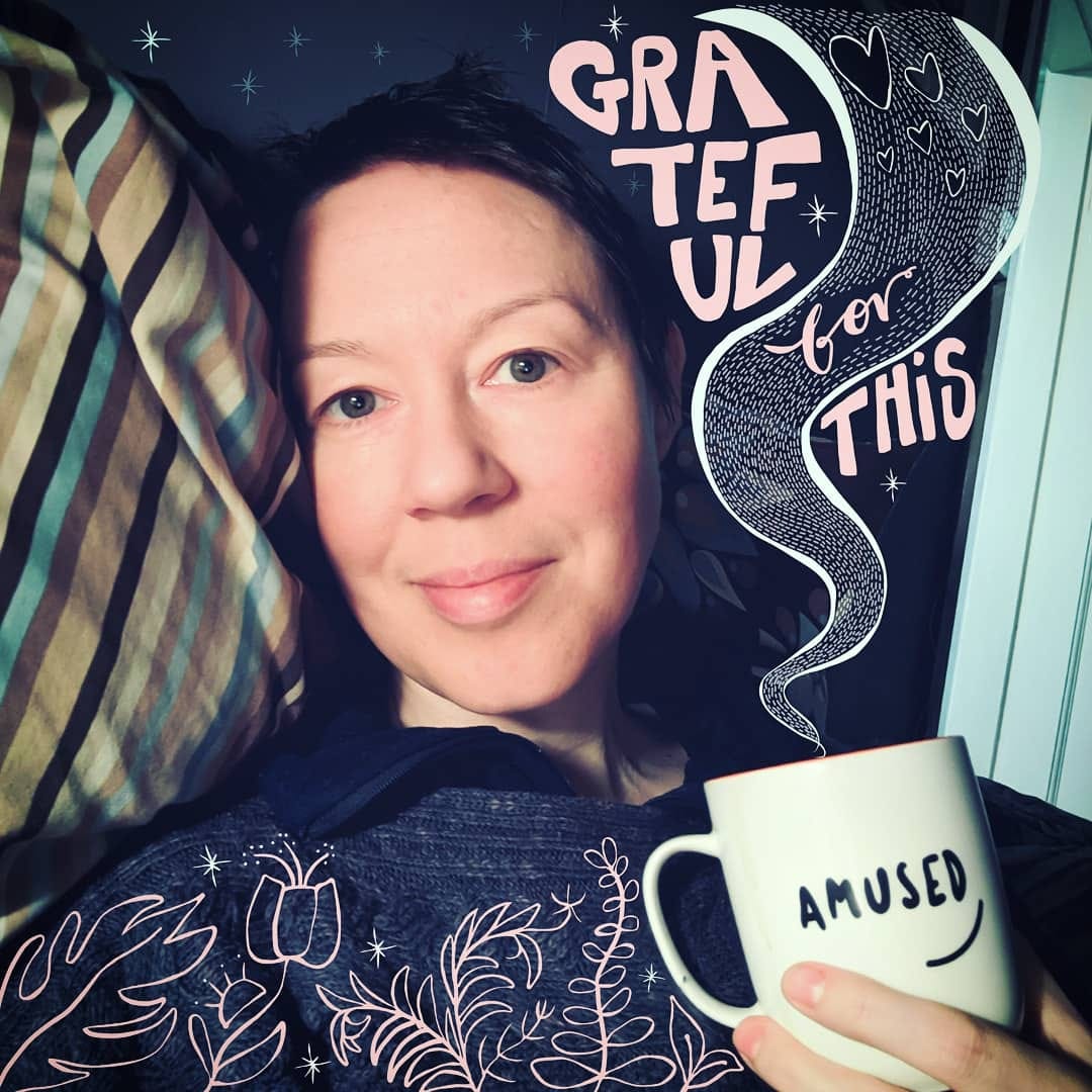 6. Square photograph of Yvie, a white woman with cropped brown hair, looking at the camera serenely. Holding a white mug in her left hand. The word “Amused” is written on the mug. Illustrated on the photograph are flowers and leaves, and steam rising from the mug with the stylised words reading: “Grateful for this.” 6. Square photograph of Yvie, a white woman with cropped brown hair, looking at the camera serenely. Holding a white mug in her left hand. The word “Amused” is written on the mug. Illustrated on the photograph are flowers and leaves, and steam rising from the mug with the stylised words reading: “Grateful for this.”