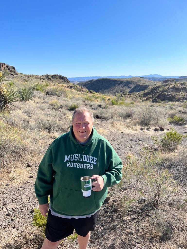 A person holding a cup in a desert

Description automatically generated