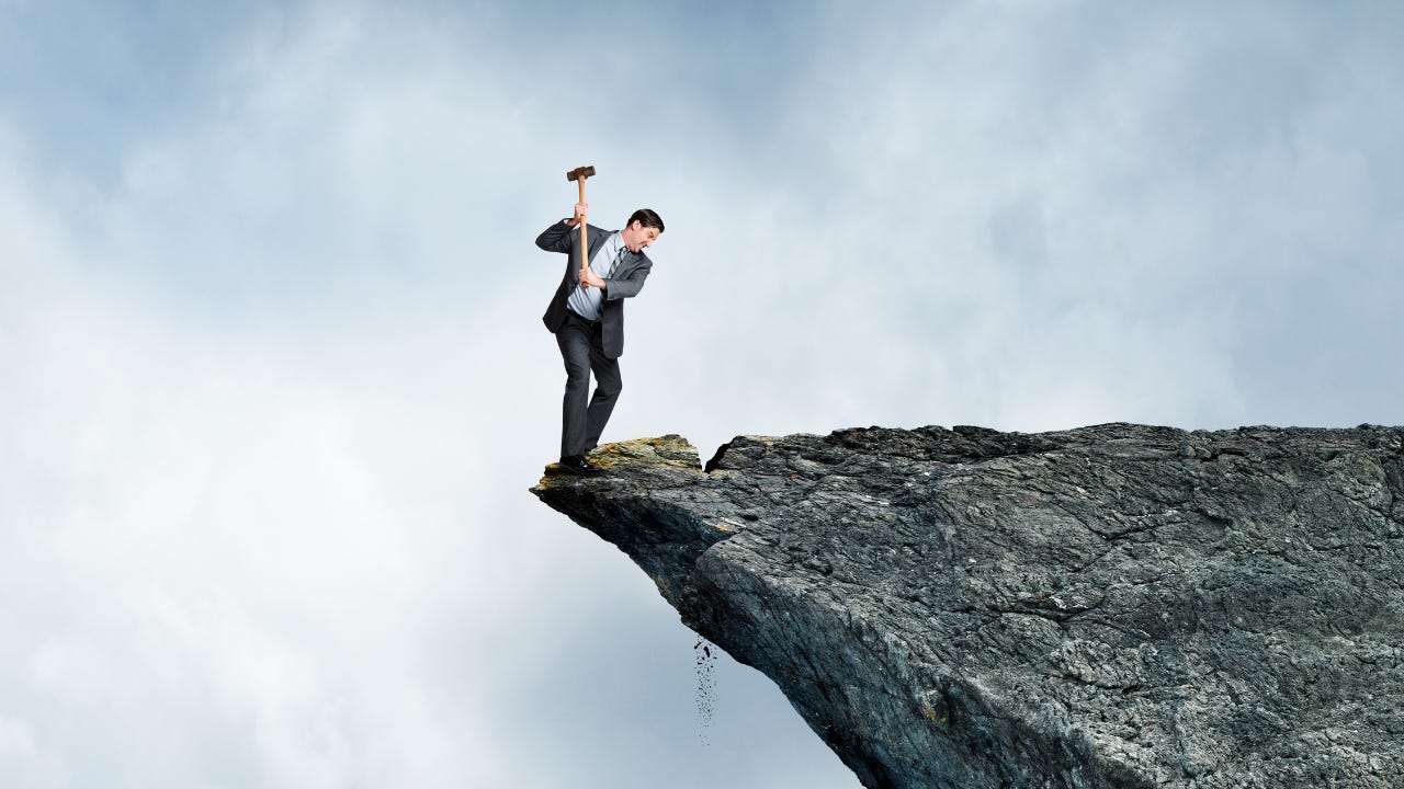 A man hitting a cliff with a hammer.