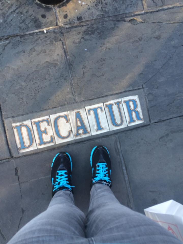 Top row: Jasmine wearing a mask in a shop, a photo of the French Market. Bottom row: a selfie of Jasmine in front of the French market, a photo of Decatur written on the street.