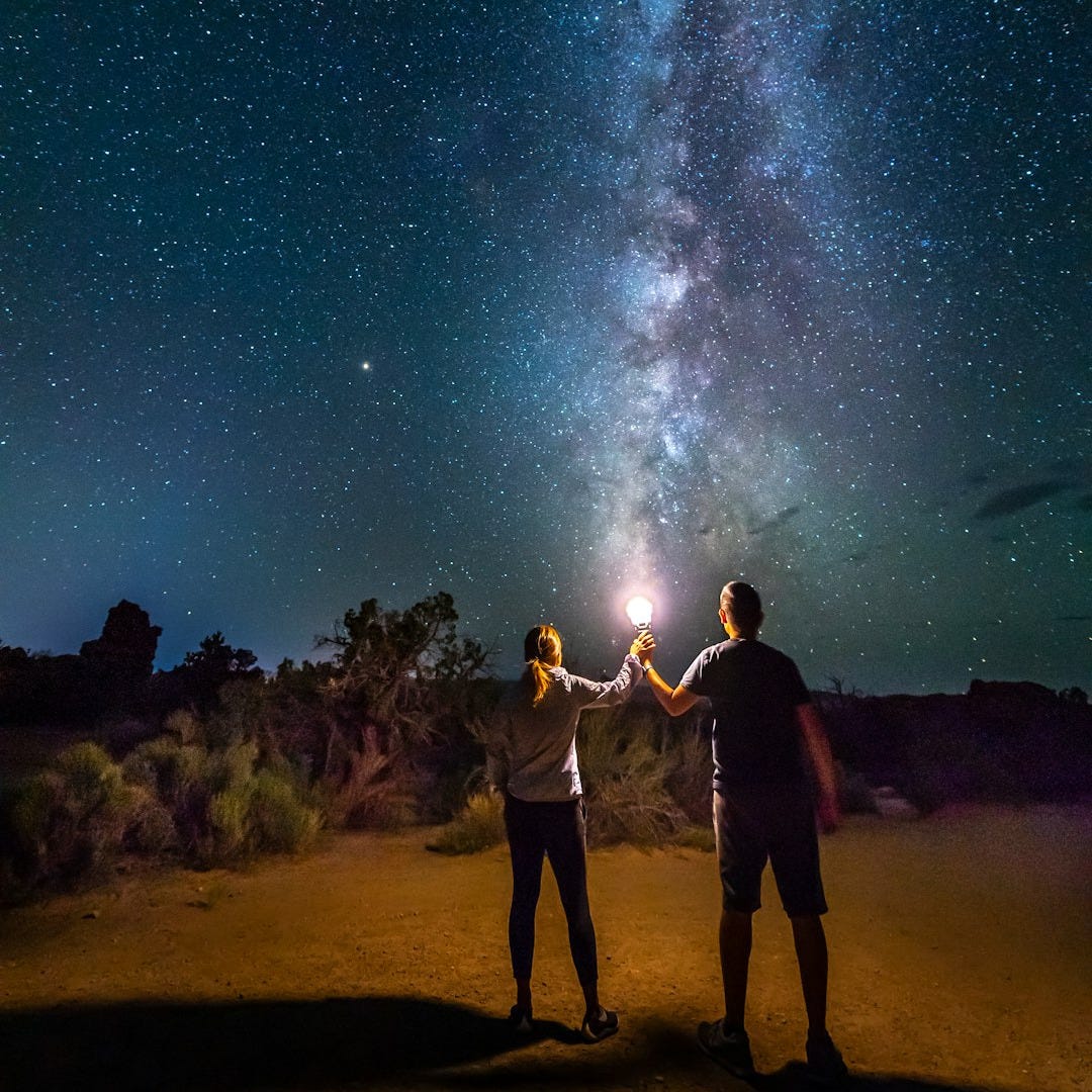 people standing on brown sand under starry night